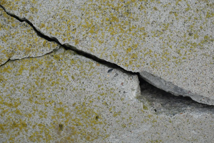 Close-up of a crack in a textured concrete surface.